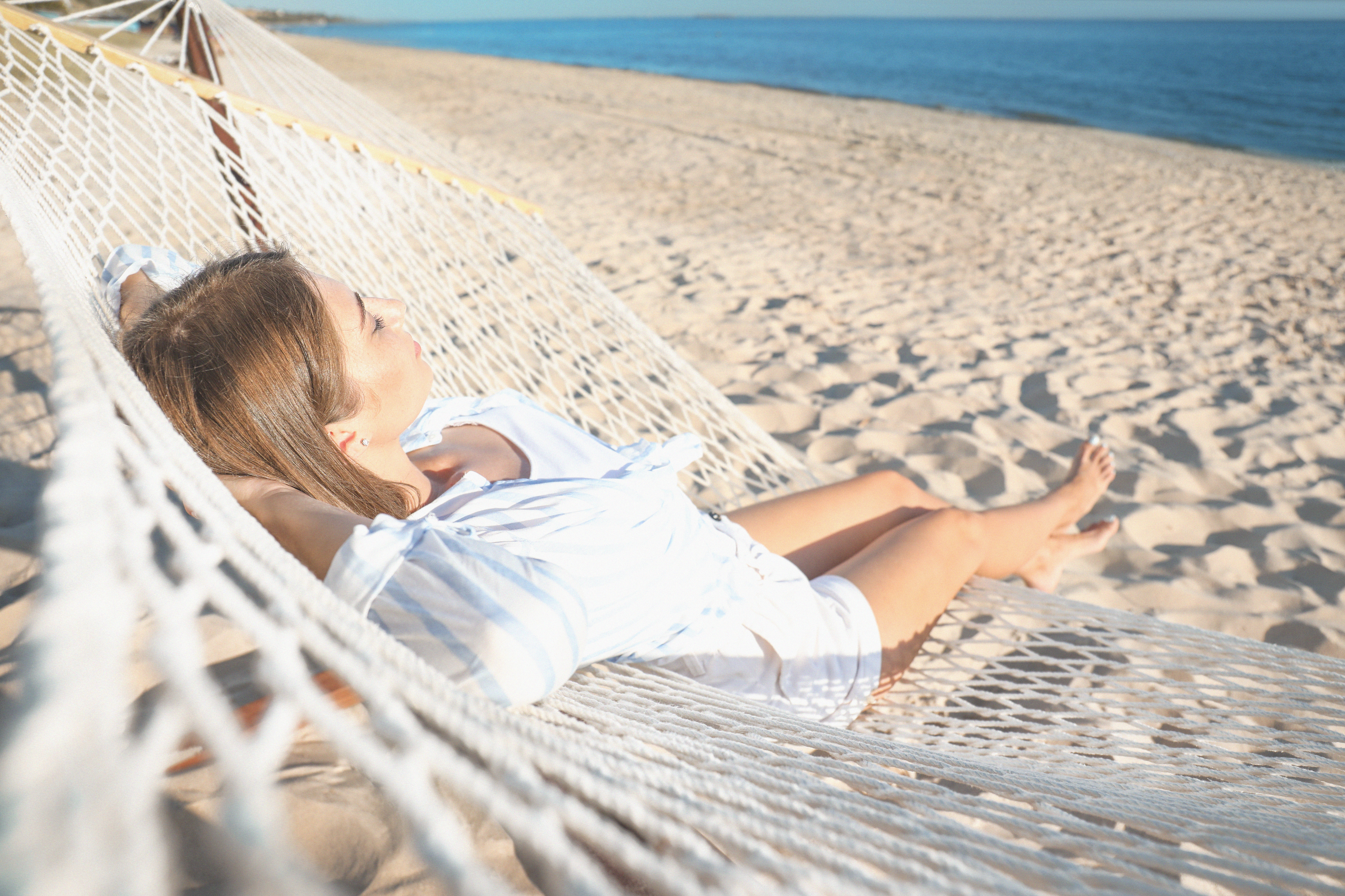 Young woman relaxing in a hammock on a beach